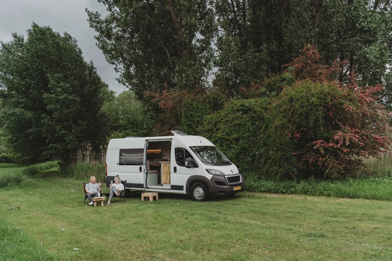 Buscamper achterdeuren open, sfeervolle camping opstelling